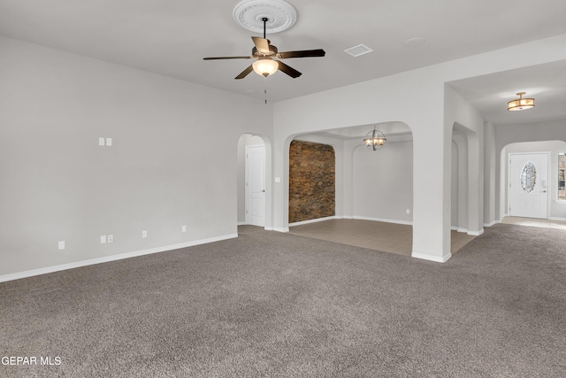 unfurnished living room with arched walkways, carpet flooring, ceiling fan, and baseboards