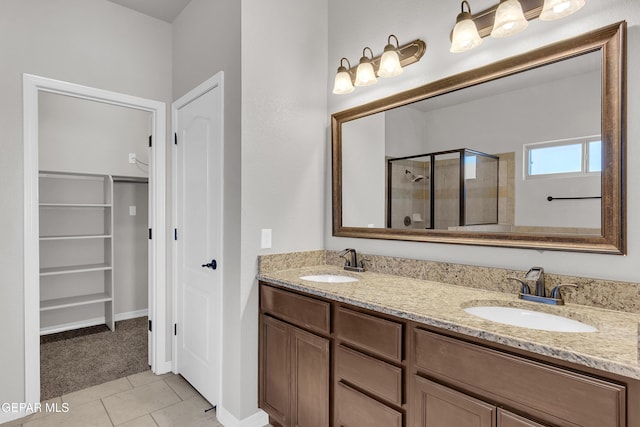 bathroom with double vanity, a shower stall, a walk in closet, and a sink