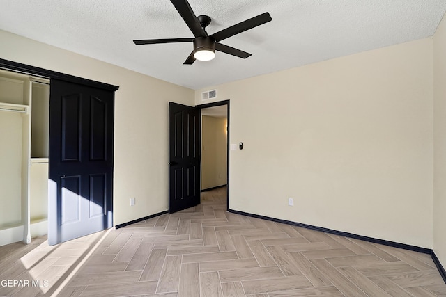 unfurnished bedroom featuring a ceiling fan, visible vents, a textured ceiling, and baseboards