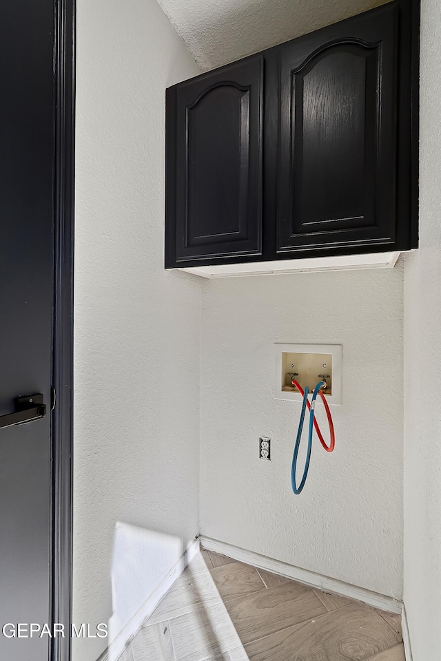 laundry room featuring hookup for a washing machine, cabinet space, and a textured wall