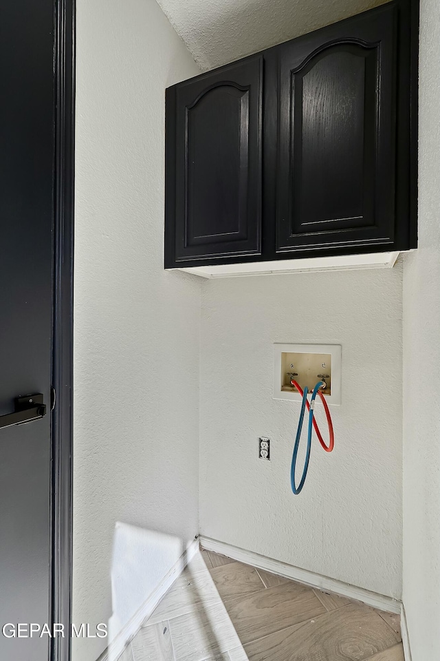 laundry room with cabinet space, hookup for a washing machine, and a textured wall