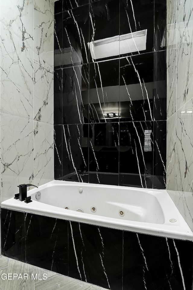 bathroom featuring tile walls and a jetted tub