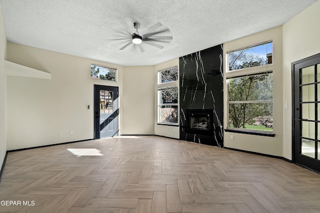 unfurnished living room featuring a premium fireplace, baseboards, and a textured ceiling