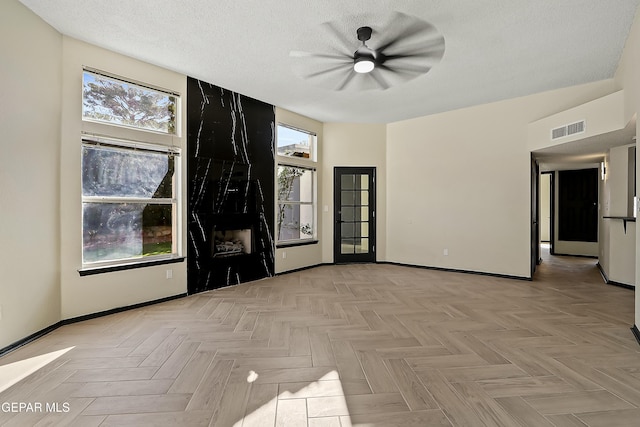 empty room featuring visible vents, a textured ceiling, and baseboards