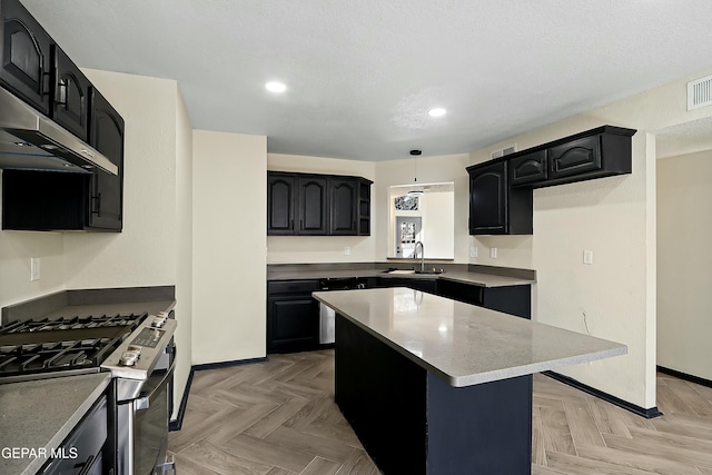 kitchen featuring hanging light fixtures, stainless steel range with gas stovetop, a kitchen island, a sink, and dark cabinets