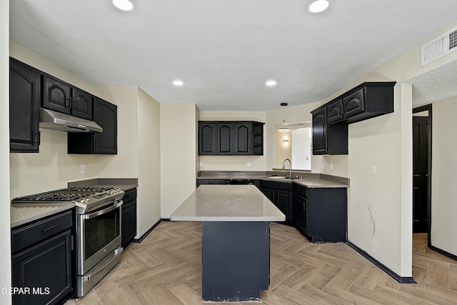 kitchen featuring stainless steel range with gas cooktop, pendant lighting, a center island, visible vents, and under cabinet range hood