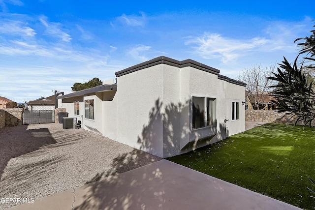 view of side of property with a patio, a yard, stucco siding, fence, and cooling unit