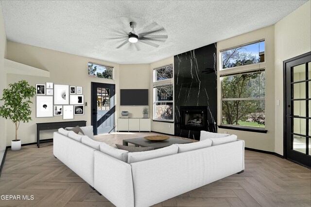 living area with a high end fireplace, a textured ceiling, and baseboards