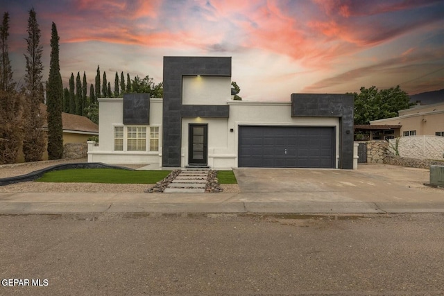 contemporary home featuring a garage, central AC unit, concrete driveway, and stucco siding