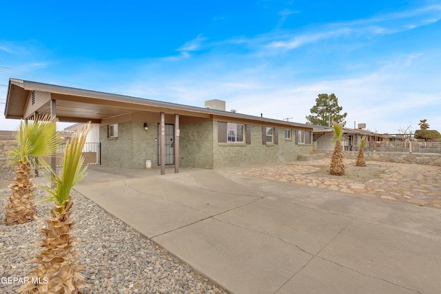 exterior space with brick siding, fence, and an attached carport