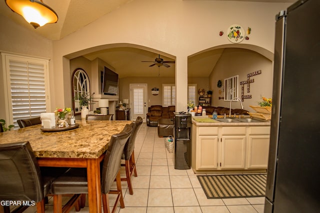 kitchen with light tile patterned flooring, a sink, a ceiling fan, open floor plan, and vaulted ceiling