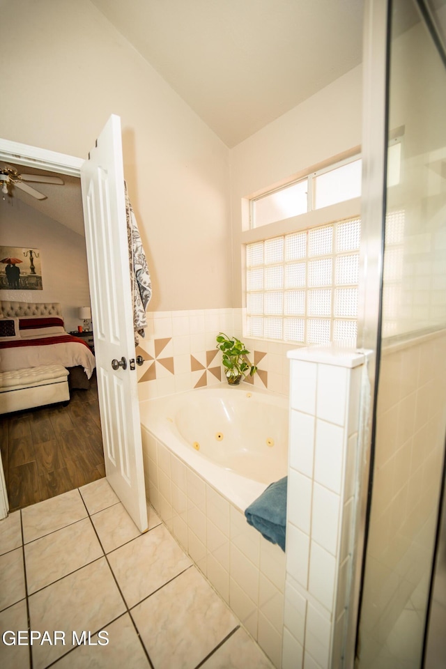 ensuite bathroom featuring tile patterned floors, vaulted ceiling, ensuite bath, and a tub with jets