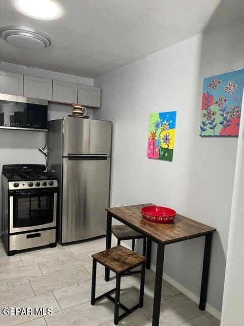 kitchen with stainless steel appliances, gray cabinets, and baseboards