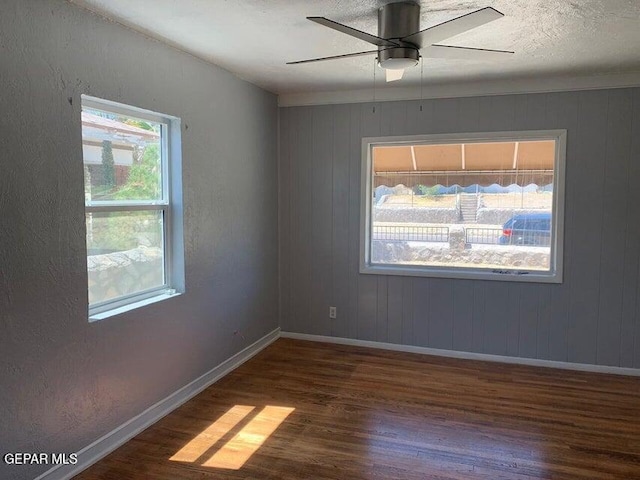 unfurnished room with dark wood-style floors, a textured ceiling, baseboards, and a ceiling fan