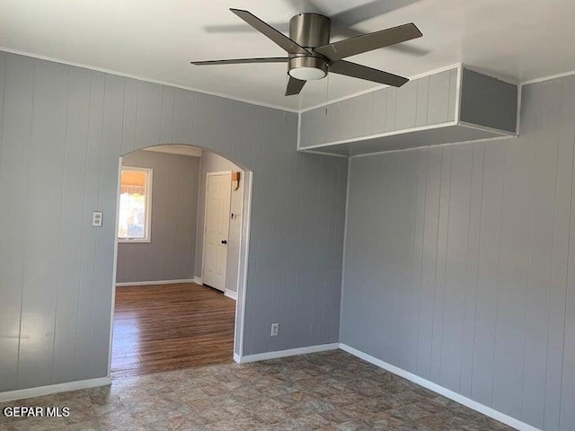 unfurnished room featuring arched walkways, crown molding, a ceiling fan, and baseboards