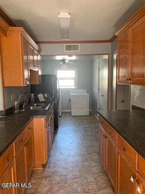 kitchen featuring visible vents, brown cabinetry, a sink, and washer / dryer