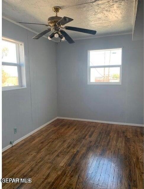 unfurnished room with dark wood-style floors, a textured ceiling, a ceiling fan, and baseboards