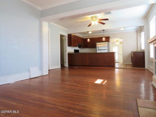 unfurnished living room with dark wood-style flooring, visible vents, ornamental molding, ceiling fan, and baseboards