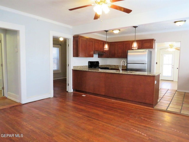 kitchen featuring a peninsula, hanging light fixtures, range, freestanding refrigerator, and dark wood finished floors