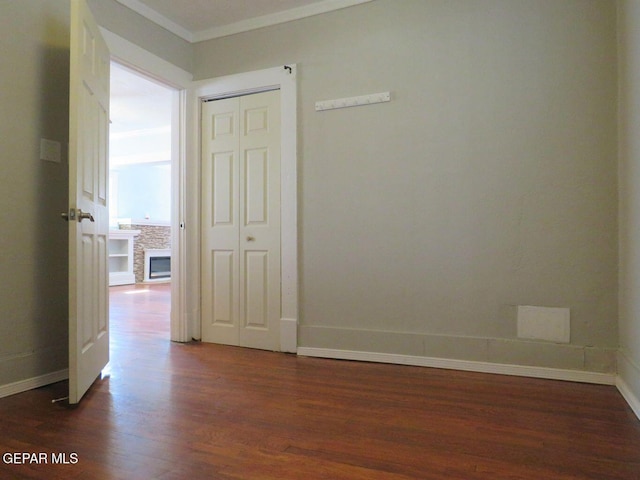 unfurnished room featuring dark wood-style floors, crown molding, and baseboards