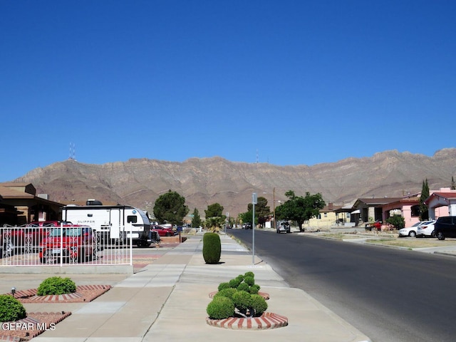 view of road featuring curbs, a residential view, a mountain view, and sidewalks