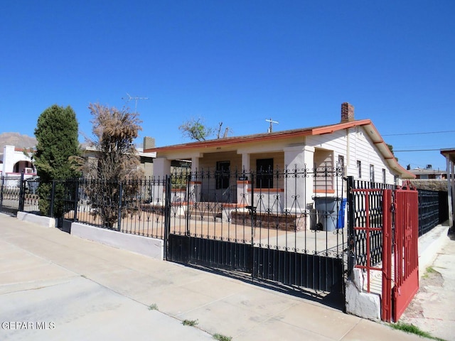 view of front facade with a fenced front yard, a gate, and a chimney