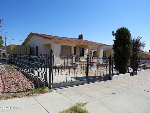 view of front of home with a fenced front yard, a gate, and a chimney