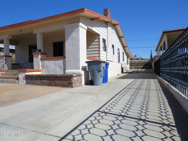 view of side of property with a chimney, fence, and a gate