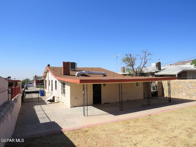 rear view of house featuring stucco siding, fence, and a patio