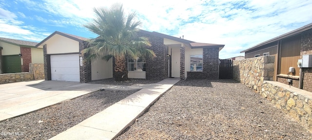 view of front of house with a garage, driveway, brick siding, and fence