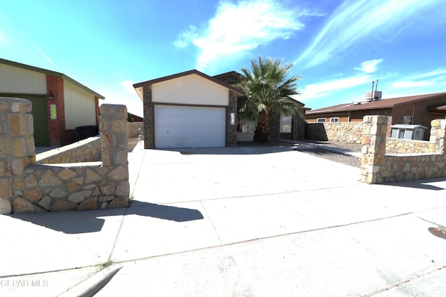 ranch-style house featuring an attached garage, a fenced front yard, and concrete driveway