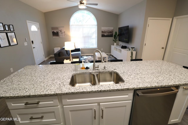 kitchen with open floor plan, vaulted ceiling, stainless steel dishwasher, white cabinetry, and a sink