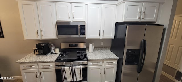 kitchen with appliances with stainless steel finishes, white cabinets, and light stone counters