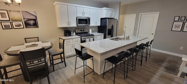 kitchen with white cabinetry, a kitchen island with sink, appliances with stainless steel finishes, and a kitchen breakfast bar