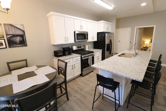 kitchen with white cabinets, an island with sink, appliances with stainless steel finishes, a breakfast bar, and a sink