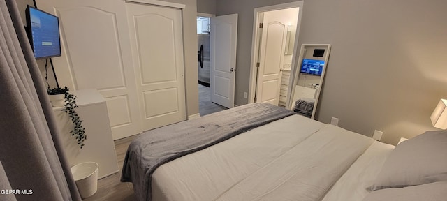 bedroom featuring dark wood-type flooring, stainless steel fridge with ice dispenser, and ensuite bathroom