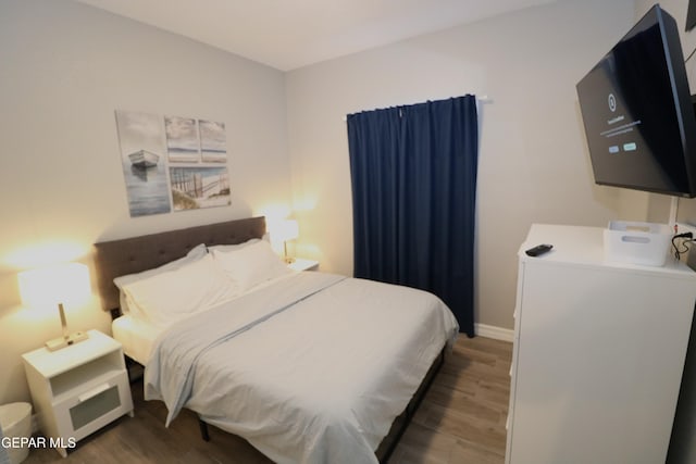 bedroom with dark wood-style flooring and baseboards