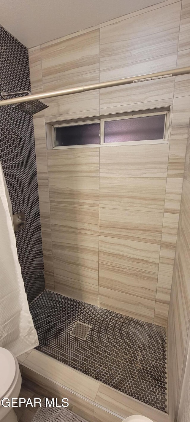 bathroom with toilet and a tile shower