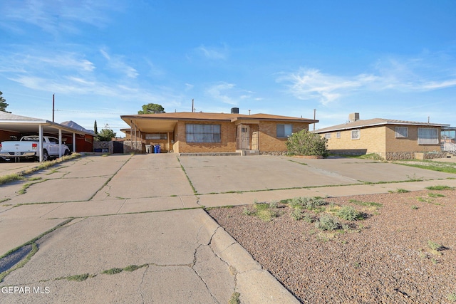 ranch-style home with driveway, an attached carport, and brick siding