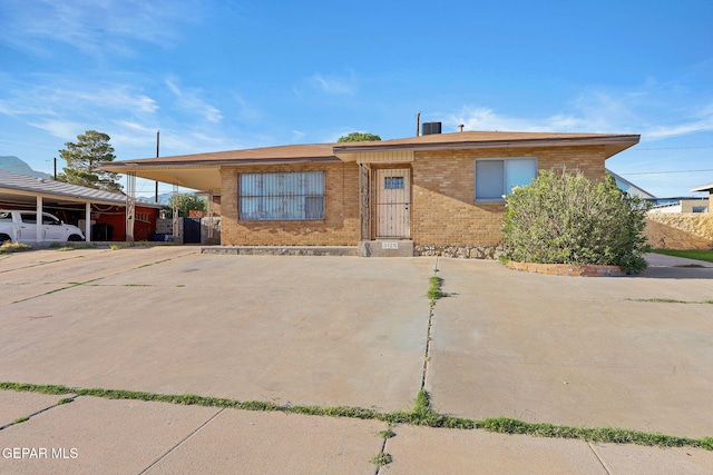 view of front facade with driveway, a carport, and brick siding