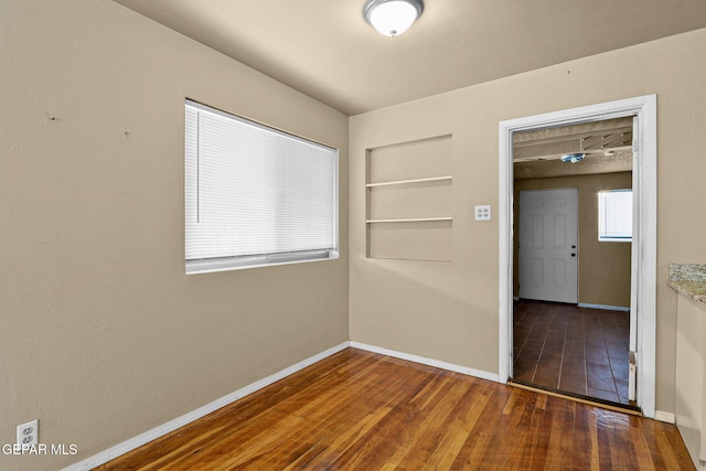 unfurnished room with dark wood finished floors and baseboards