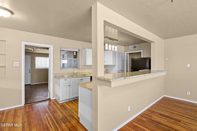 kitchen featuring light stone counters, visible vents, dark wood-type flooring, freestanding refrigerator, and white cabinets