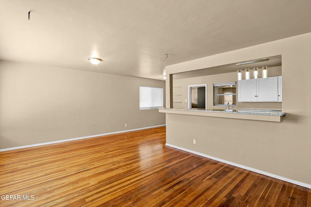 unfurnished living room with baseboards and wood finished floors