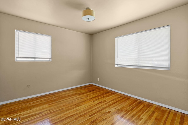 unfurnished room with light wood-style floors, a healthy amount of sunlight, and baseboards