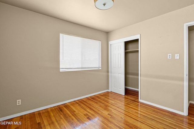 unfurnished bedroom with light wood-style floors, baseboards, and a closet