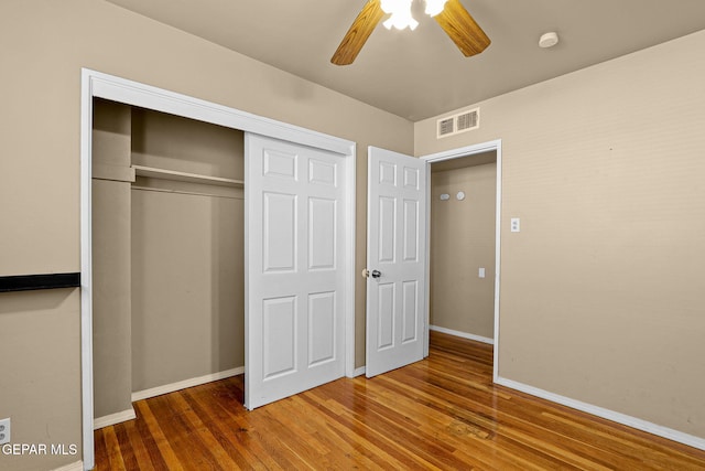 unfurnished bedroom with ceiling fan, wood finished floors, visible vents, baseboards, and a closet