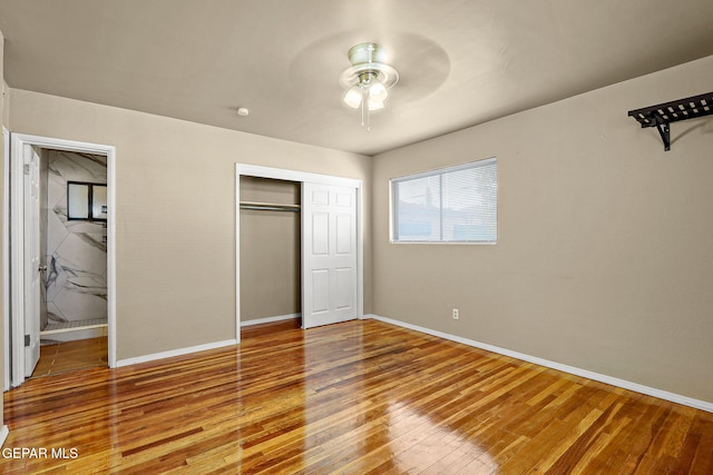 unfurnished bedroom with a closet, wood finished floors, a ceiling fan, and baseboards