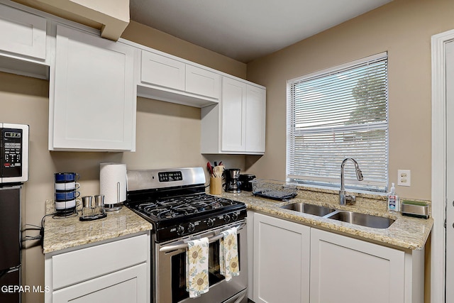 kitchen with stainless steel gas range oven, white cabinets, and a sink