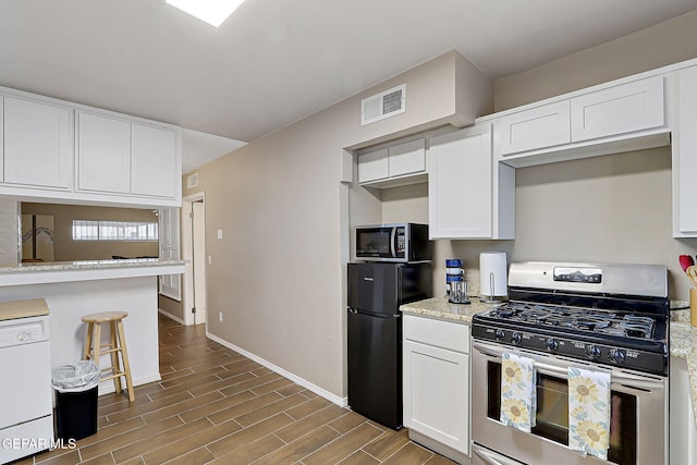 kitchen with visible vents, white cabinets, freestanding refrigerator, white dishwasher, and gas stove