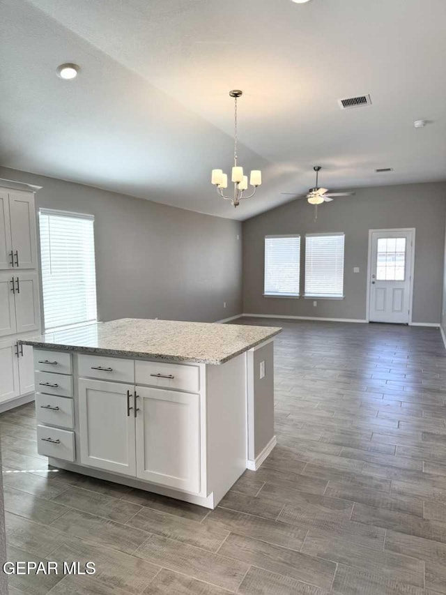 kitchen with visible vents, open floor plan, a center island, decorative light fixtures, and white cabinetry